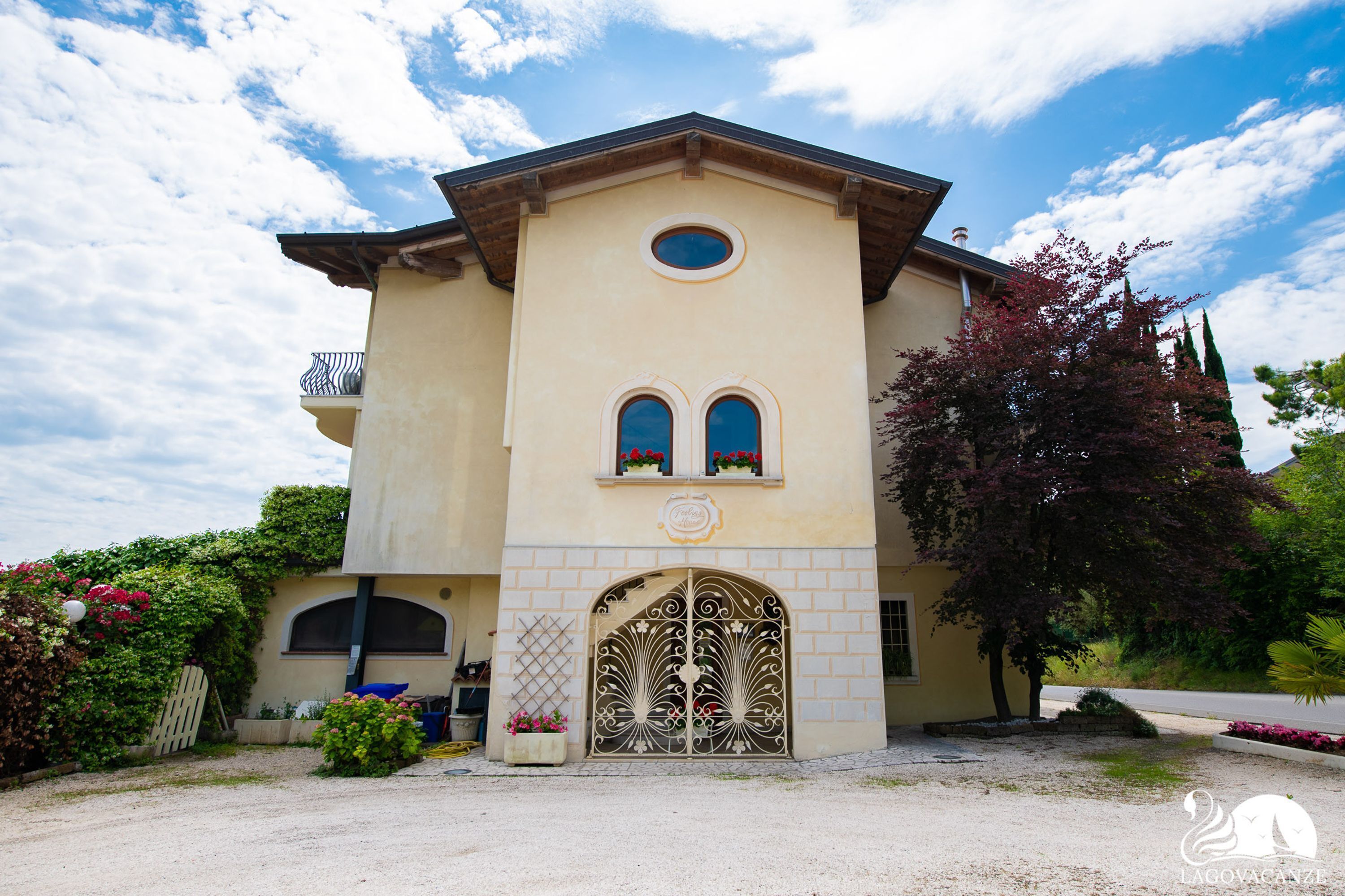 Un bâtiment à deux étages, doté d’une façade beige, d’une fenêtre circulaire centrale et de deux fenêtres en arc surmontées de jardinières.