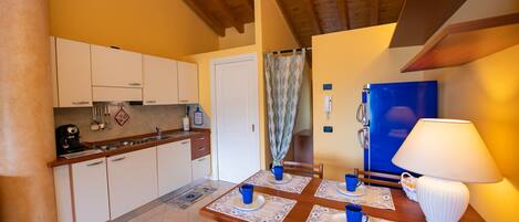 Una cocina acogedora con armarios de madera, una mesa de comedor con tazas y platos azules, y un refrigerador azul.