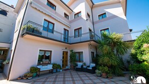 Un edificio de varios pisos con un patio que cuenta con asientos exteriores y plantas en macetas.
