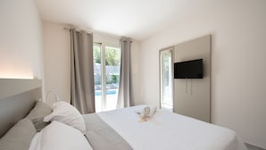 Habitación de hotel con cama, televisor montado en la pared y vista a una piscina.