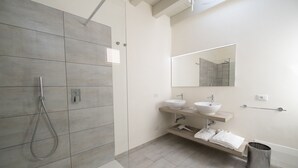 A modern bathroom with a walk-in shower, two sinks, a mirror, and a towel rack. - L Agrumeto - Il Pompelmo (Manerba del Garda)