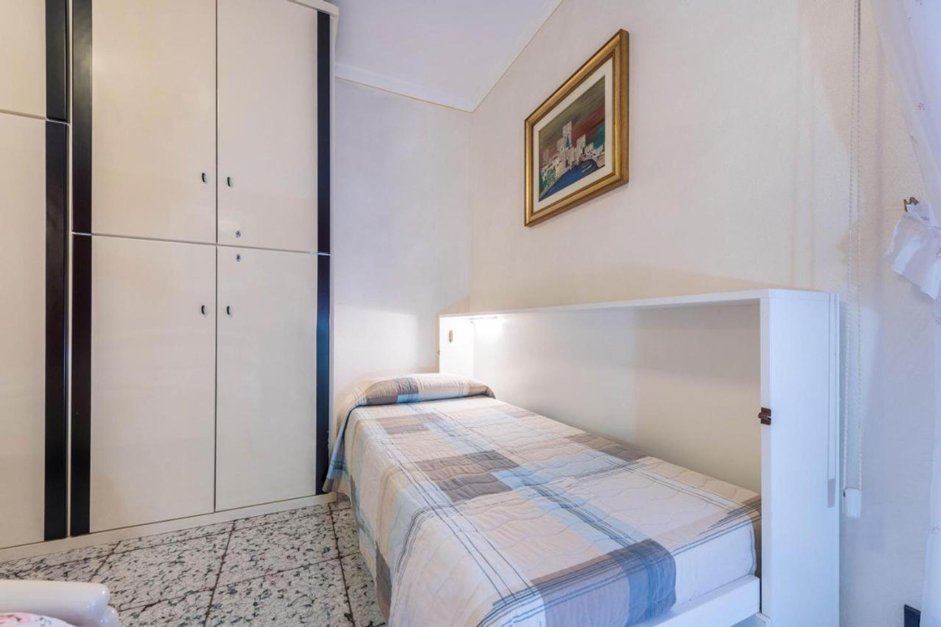 Ein Schlafzimmer mit einem Bett, einem Kleiderschrank und einem Bild an der Wand.
