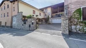 A multi-story building with a stone entrance, a parking area, and a garage. - Casa Vacanze Baccolo - Appartamento Lucia (Polpenazze del Garda)