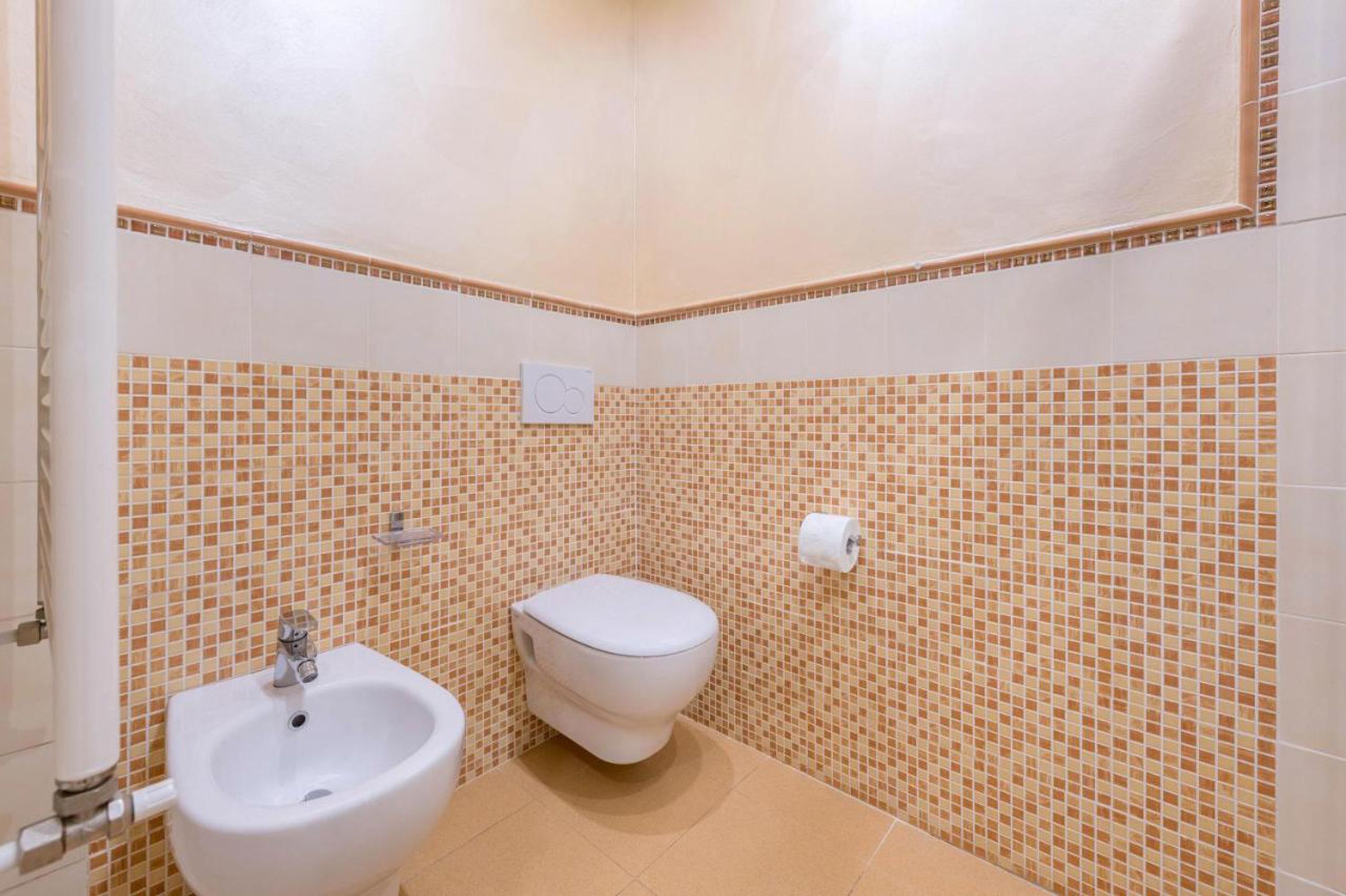 Ein Badezimmer mit Bidet, Toilette und gefliesten Wänden.