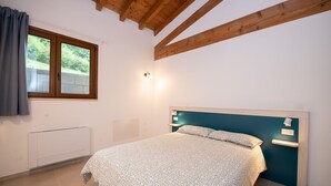 Un dormitorio con cama, ventana, luz empotrada en la pared y radiador.