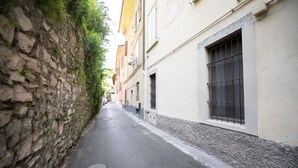A narrow street flanked by stone walls and buildings with barred windows.