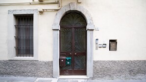 A building entrance with a large arched door, a barred window, and a mailbox.