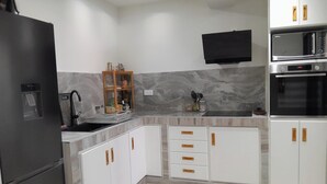 A modern kitchen with white cabinets, a black refrigerator, a microwave, and a built-in oven.
