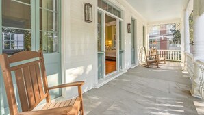A porch with a wooden bench, a dining table with chairs, and a view of the interior through open doors. - Beautifully Restored 3-Bedroom Home with Private Ensuite (Charleston)