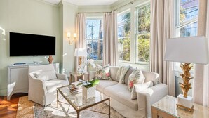 A living room with a sofa, armchairs, a coffee table, and a TV. - Beautifully Restored 3-Bedroom Home with Private Ensuite (Charleston)