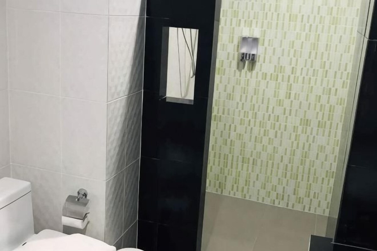 A bathroom with a toilet, a towel rack, and a shower area.