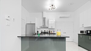Una cocina moderna con armarios blancos, una isla central y una campana extractora de acero inoxidable.
