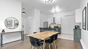 Una cocina moderna con armarios blancos, una mesa de comedor de madera y sillas negras.