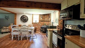 A cozy kitchen with wooden floors, a brick wall, a large clock, and modern appliances. - Peaceful, relaxing, family friendly, fully updated 3-bedroom house in Bellville (Bellville)