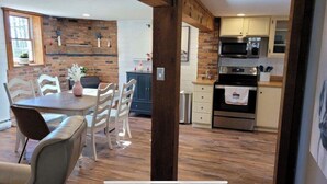 A modern kitchen with a brick wall, wooden beams, and a dining area with a table and chairs. - Peaceful, relaxing, family friendly, fully updated 3-bedroom house in Bellville (Bellville)