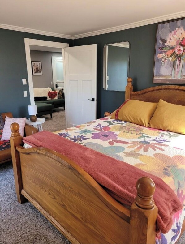 A bedroom with a wooden bed, floral bedspread, and a door leading to another room. - Peaceful, relaxing, family friendly, fully updated 3-bedroom house in Bellville (Bellville)