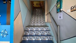 A staircase with patterned tiles, a handrail, and a wall-mounted sign. - Ang Lee Holiday Stay (Semporna)