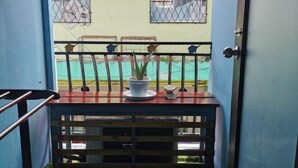 A balcony with a potted plant, a small table, and a railing. - Ang Lee Holiday Stay (Semporna)
