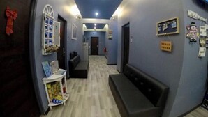 A hallway with a reception desk, a bench, and a wall with holiday decorations. - Ang Lee Holiday Stay (Semporna)