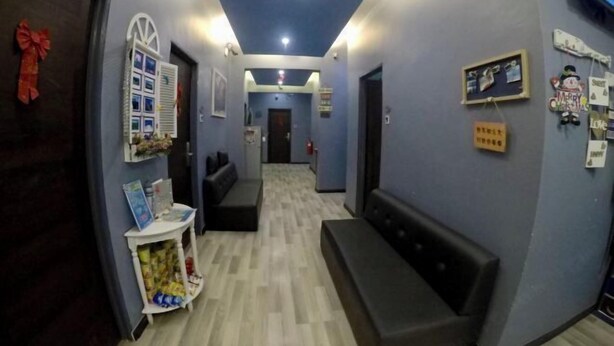 A hallway with a reception desk, a bench, and a wall with holiday decorations. - Ang Lee Holiday Stay (Semporna)