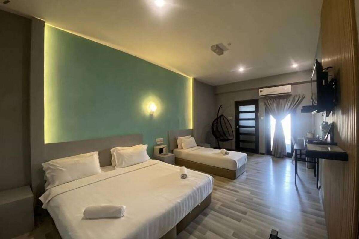 A hotel room with two beds, a TV, a desk, and a chair.
