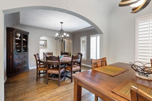 Ein Essbereich mit Holztisch und Stühlen, einer Chandelüster und einem Schrank mit Glastüren.