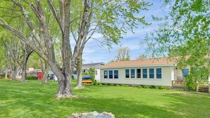 A house with a fire pit in the yard, surrounded by trees and a well-maintained lawn. - Shawano Lake House w/ Boat Dock, Kayaks, & Grill! (Cecil)