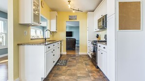 A kitchen with white cabinets, a granite countertop, and a tiled floor. - Shawano Lake House w/ Boat Dock, Kayaks, & Grill! (Cecil)