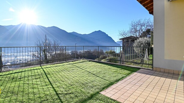 Une pelouse bien entretenue, agrémentée d’une terrasse carrelée et d’une clôture en métal.