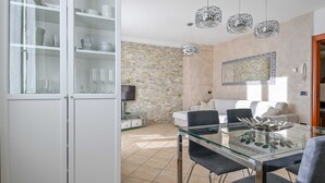Un salon moderne avec un mur en pierre, une table à manger en verre et un canapé.
