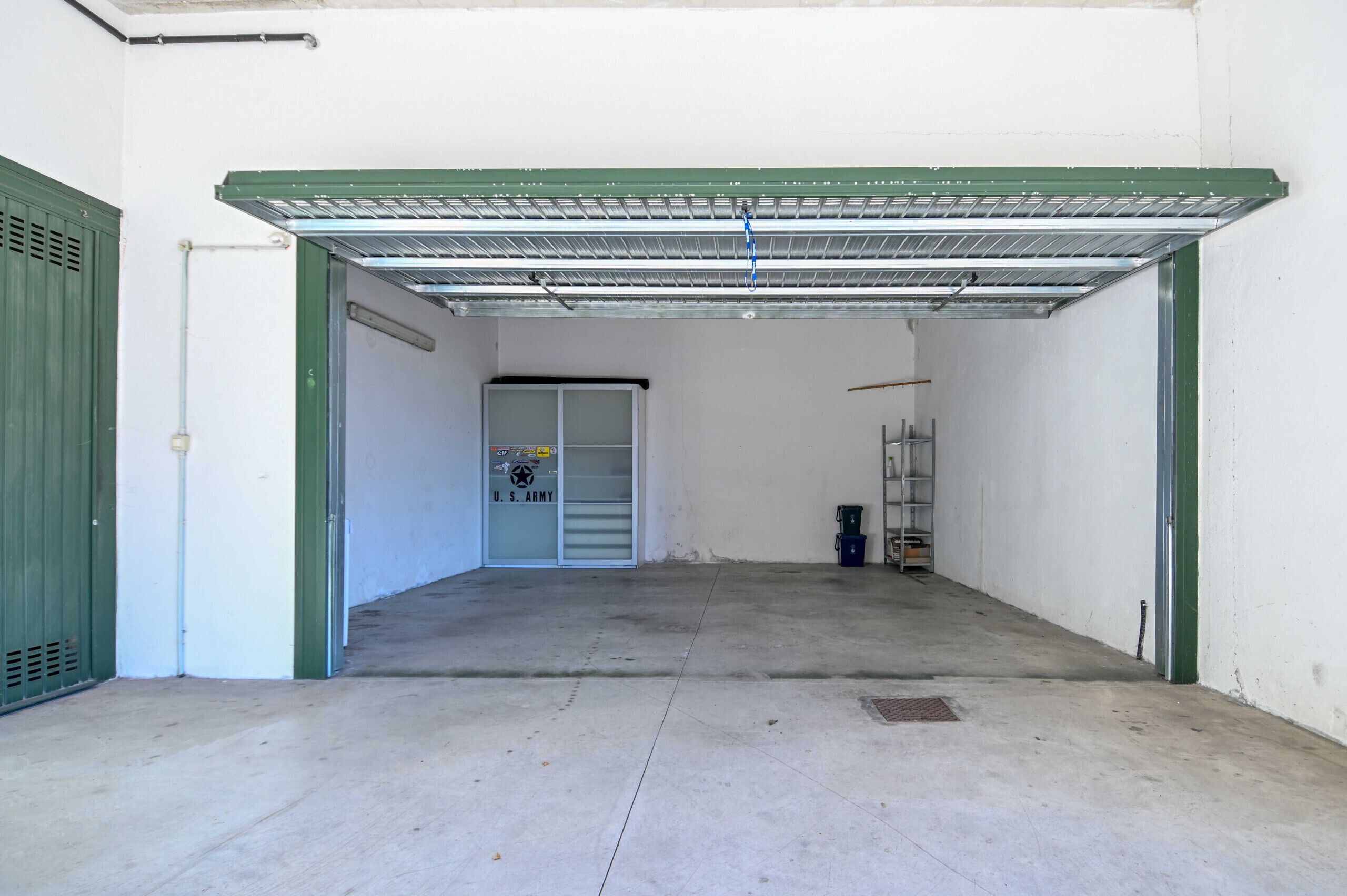 Un grand garage vide, doté d’un toit en métal et de bordures vertes.