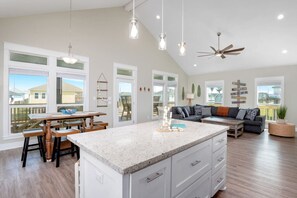A spacious living area with a kitchen island, a dining table, and a sofa. - Two Adjacent Cabins, Sleeps 18 (Bolivar Peninsula)