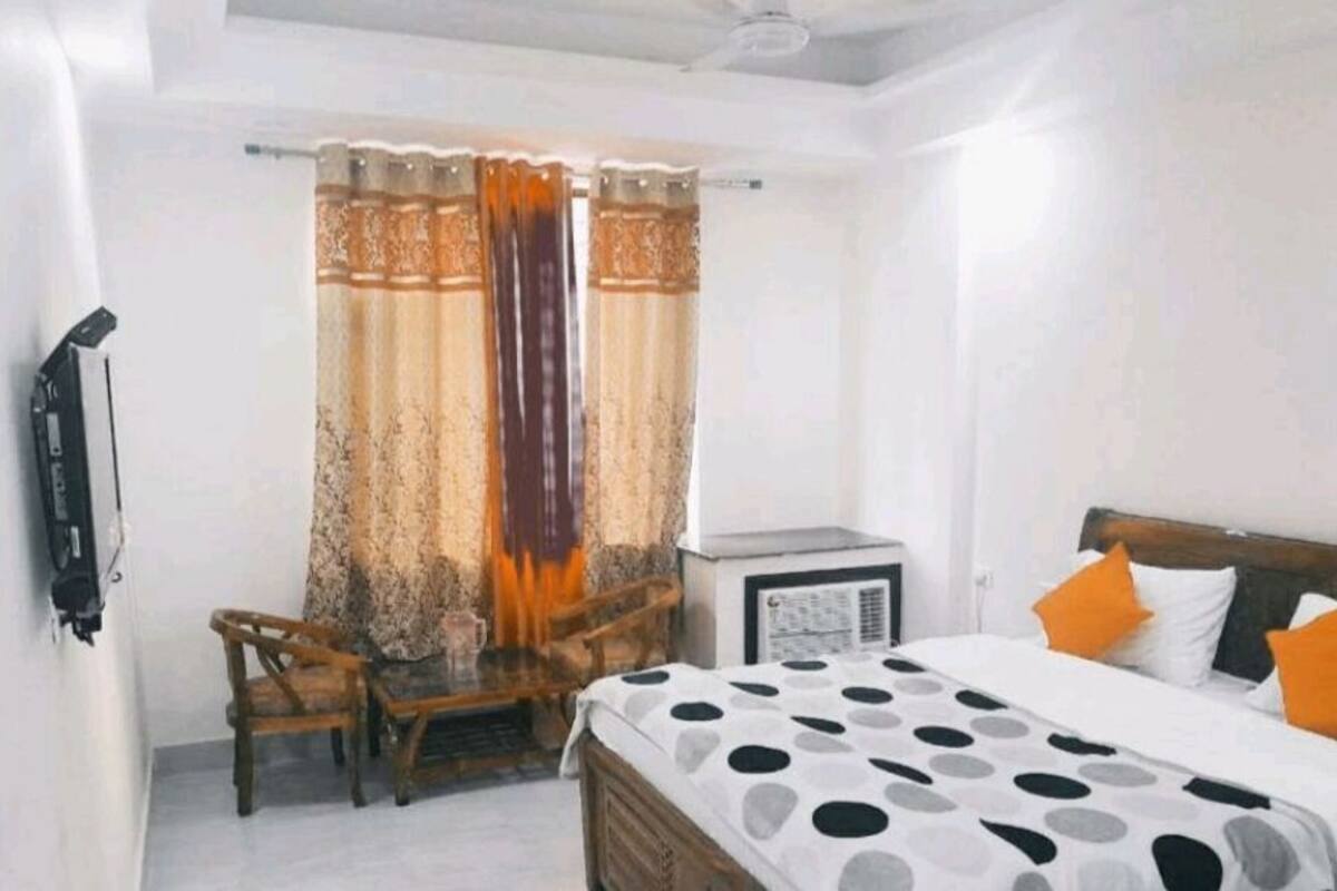 A bedroom with a bed, two chairs, a small table, and a heater.