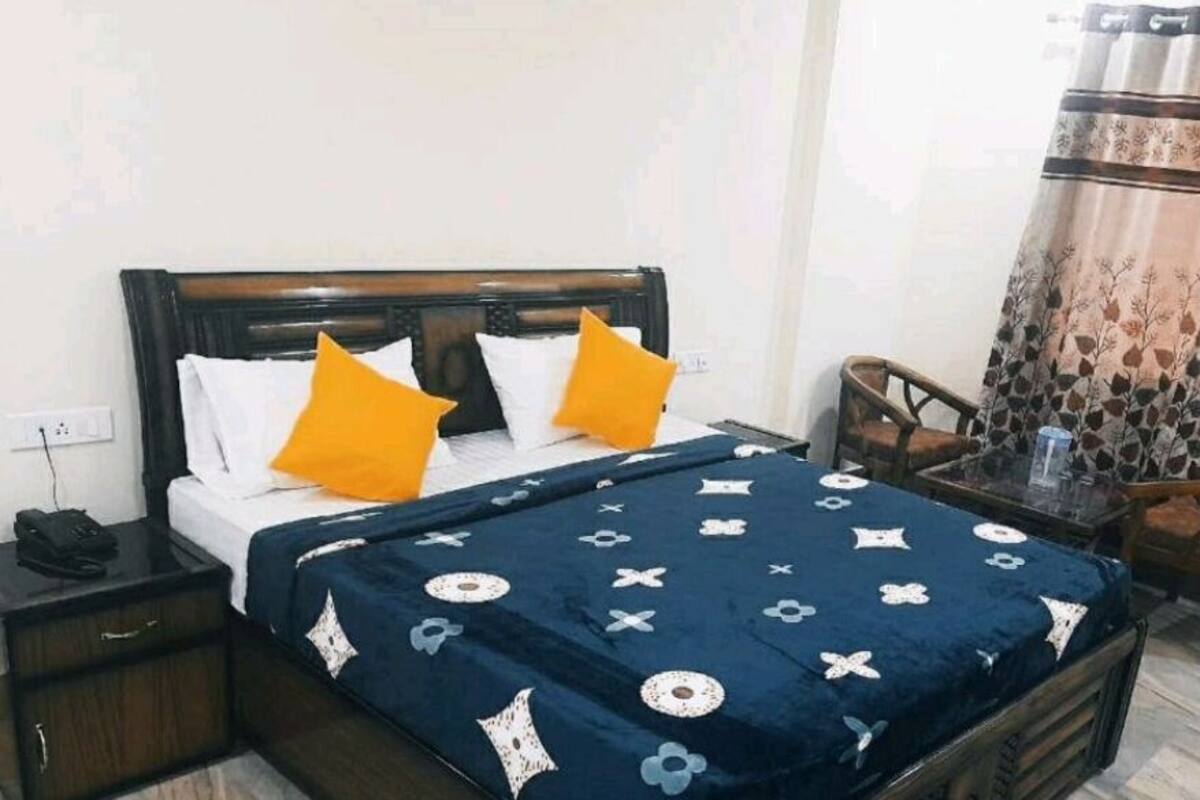 A bedroom with a bed, nightstand, chair, and a table with a glass top.