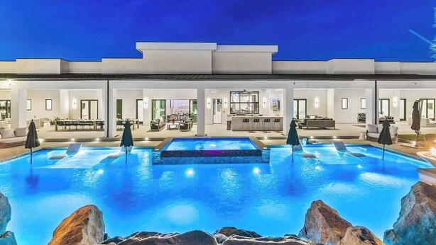 A modern hotel with a large outdoor pool, multiple rooms with large windows, and a well-lit exterior. - Private Estate-Waterslide-Theatre-Sauna-Pickleball (Indio)