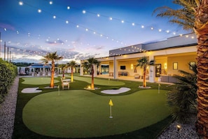 A modern house with a well-maintained lawn, outdoor seating, and string lights.
