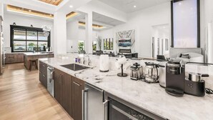 A modern kitchen with a marble countertop, built-in appliances, and a large window. - Private Estate-Waterslide-Theatre-Sauna-Pickleball (Indio)