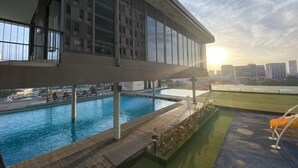 A rooftop pool area with a view of the city skyline, a covered deck, and a lounge area with chairs. - The Pines by Amanjiwa (Melaka)