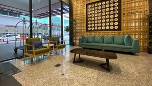 A lobby with a green sofa, wooden chairs, and a coffee table. - The Pines by Amanjiwa (Melaka)