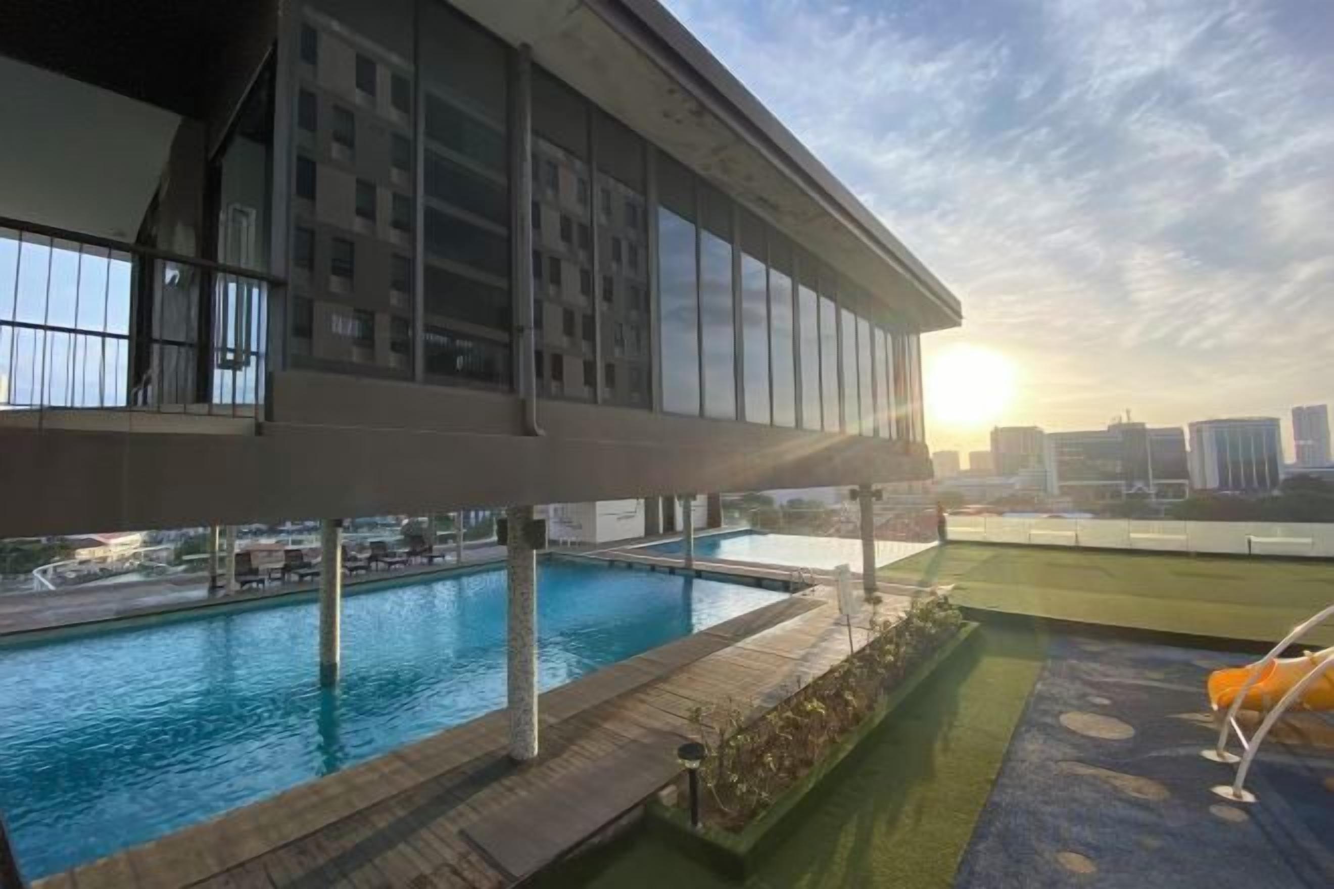 A rooftop pool with a view of the city skyline, a covered outdoor area, and a lounge chair.