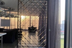 Un interior moderno con un separador geométrico, un comedor con mesa y sillas, y vistas a través de una puerta de cristal.