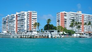 A waterfront hotel with multiple floors, balconies, and a marina with boats. - Private Island 1BR Condo with Oceanview, Pool View, 500MB WiFi & A/C (Fajardo)