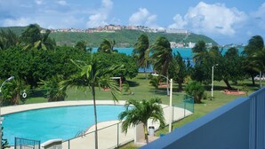 A swimming pool with a view of a coastal town and a hill in the background. - Private Island 1BR Condo with Oceanview, Pool View, 500MB WiFi & A/C (Fajardo)