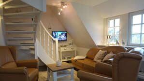 Un salon confortable avec un escalier, un téléviseur et une fenêtre donnant sur un beau paysage.