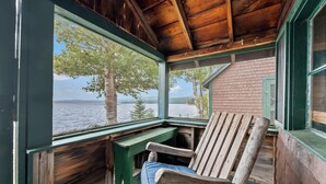 Une cabane en bois avec un banc et une table près d’une fenêtre donnant sur un lac.