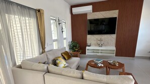Ein modernes Wohnzimmer mit einer Eckcouch, einem Flachbildfernseher und einer Wand als Holzdekor.
