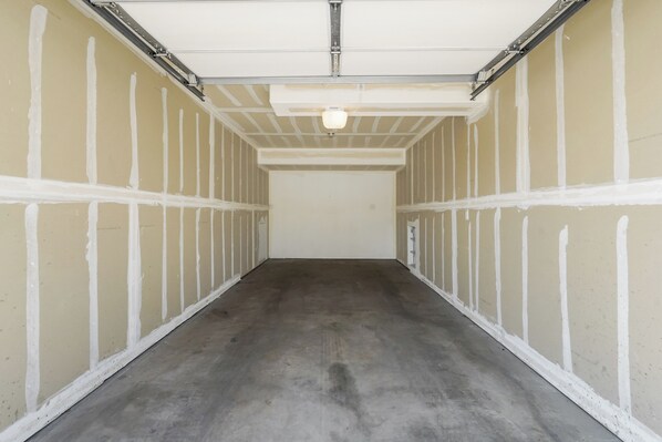 A long, narrow hallway with white walls and a concrete floor, leading to a plain white ceiling with a light fixture. - OCC Complex (Colorado Springs)