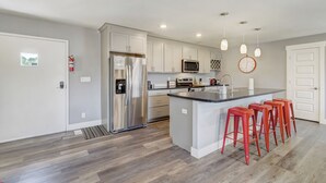 A modern kitchen with white cabinets, stainless steel appliances, and a central island with red bar stools.