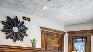 Una sala de estar con chimenea, una puerta grande de madera, una mesa de centro de vidrio y un sofá.