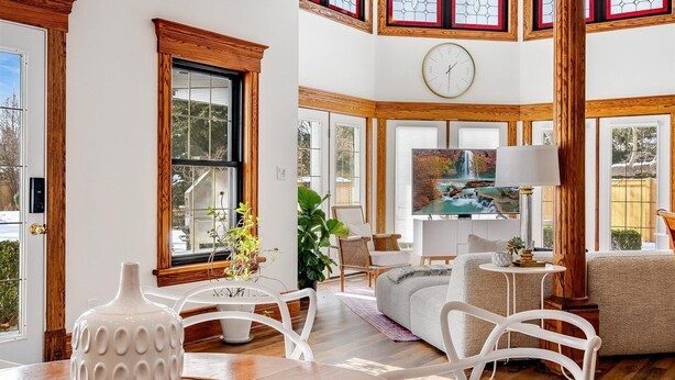 Un salón amplio con una mesa de comedor de madera, sillas blancas y un ventanal con vistas a una cascada.